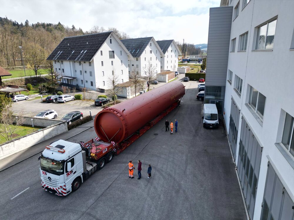 Freitag-Abend, 27. März 2026: Der Koloss ist aufgeladen und fachmännisch fixiert. Die Tieflader-Komposition mit der Gesamtlänge von gut 30 m ist bereit zur Abfahrt. Im Hintergrund die drei Jenni-MFH in Oberburg BE, alle ganzjährig beheizt mit Solarwärme.